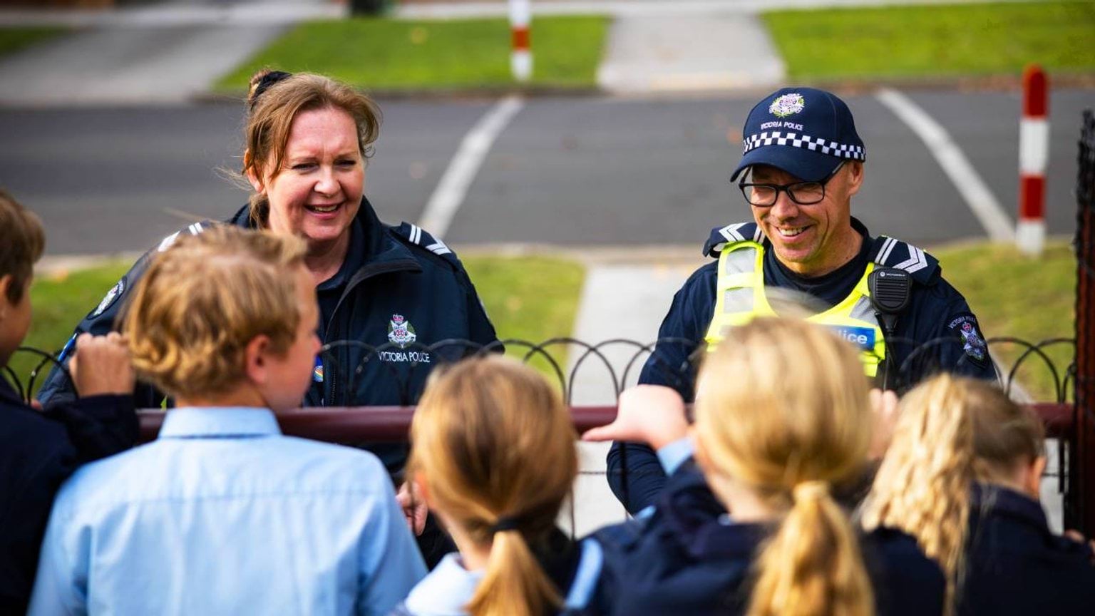 Police Life stories - Two smiling officers talking to school children outside