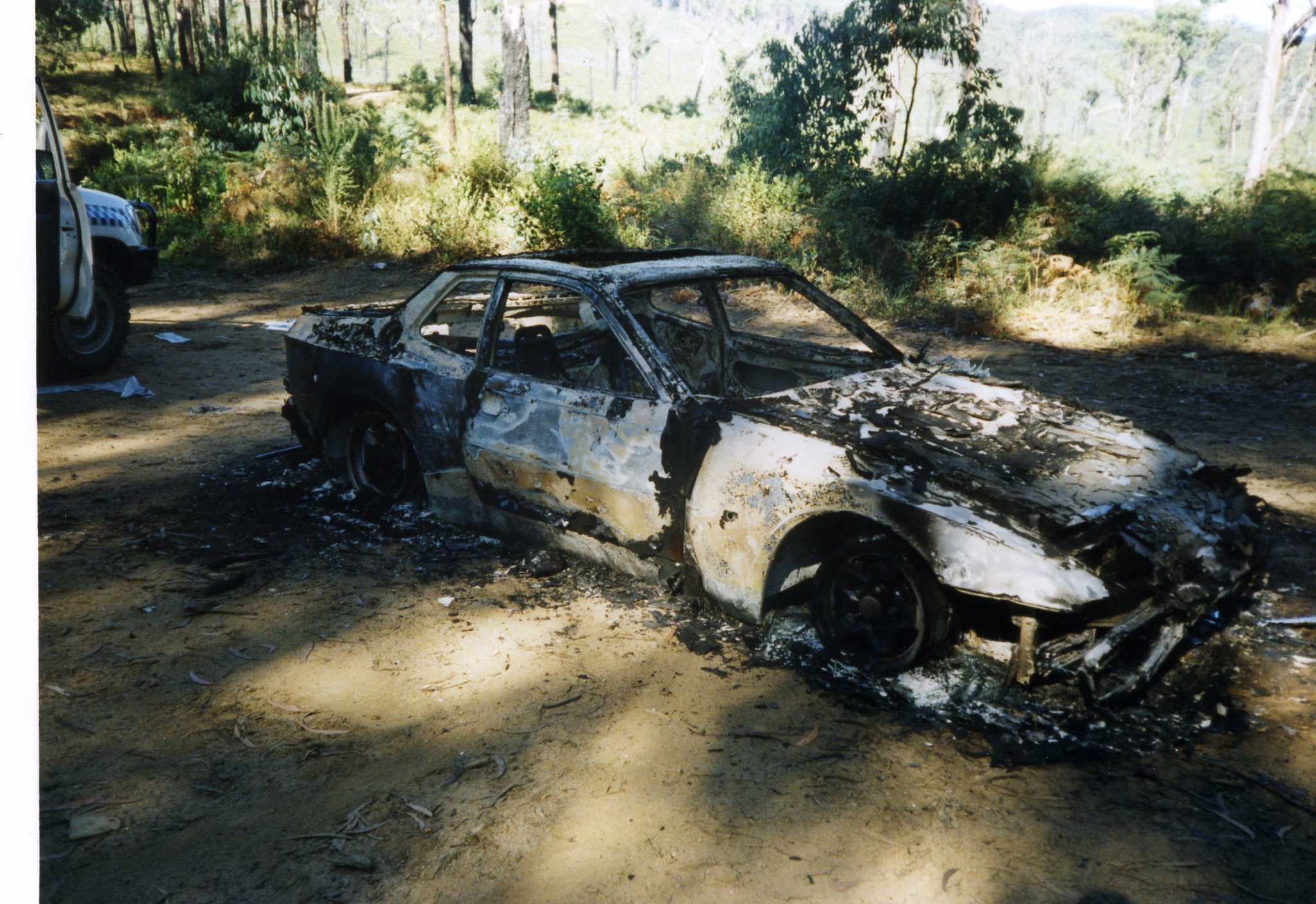 The wreckage of a burnt red Porsche coupe, registration JD 944 