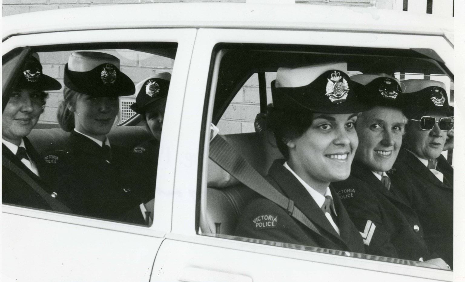 Female police officers wearing police uniform, inside a police vehicle.
