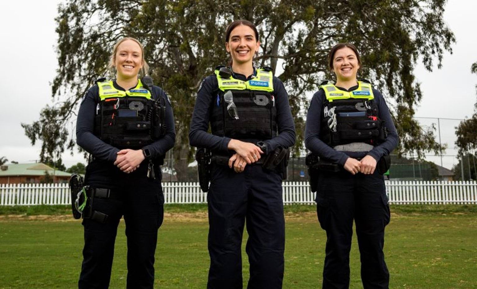 Three female officers in police uniform stand facing the camera and smiling.