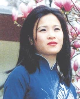 Missing person Huong Thi Thu Nguyen. Huong looks away from the camera in front of a cherry blossom tree. She has mid-length black hair. She is Vietnamese and of Asian appearance. She wears red lipstick and a blue shirt with a collar.