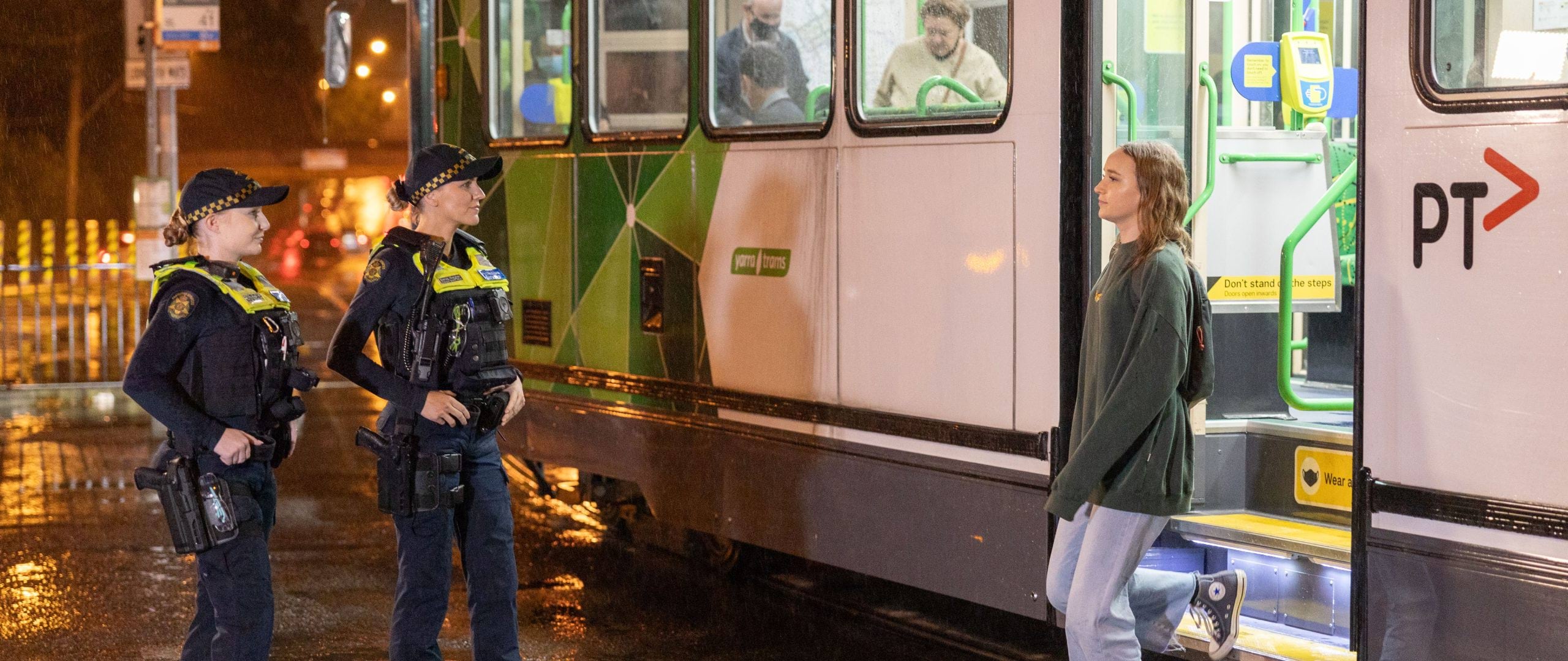 Personal safety in public - Young person getting off night tram talking to two PCOs