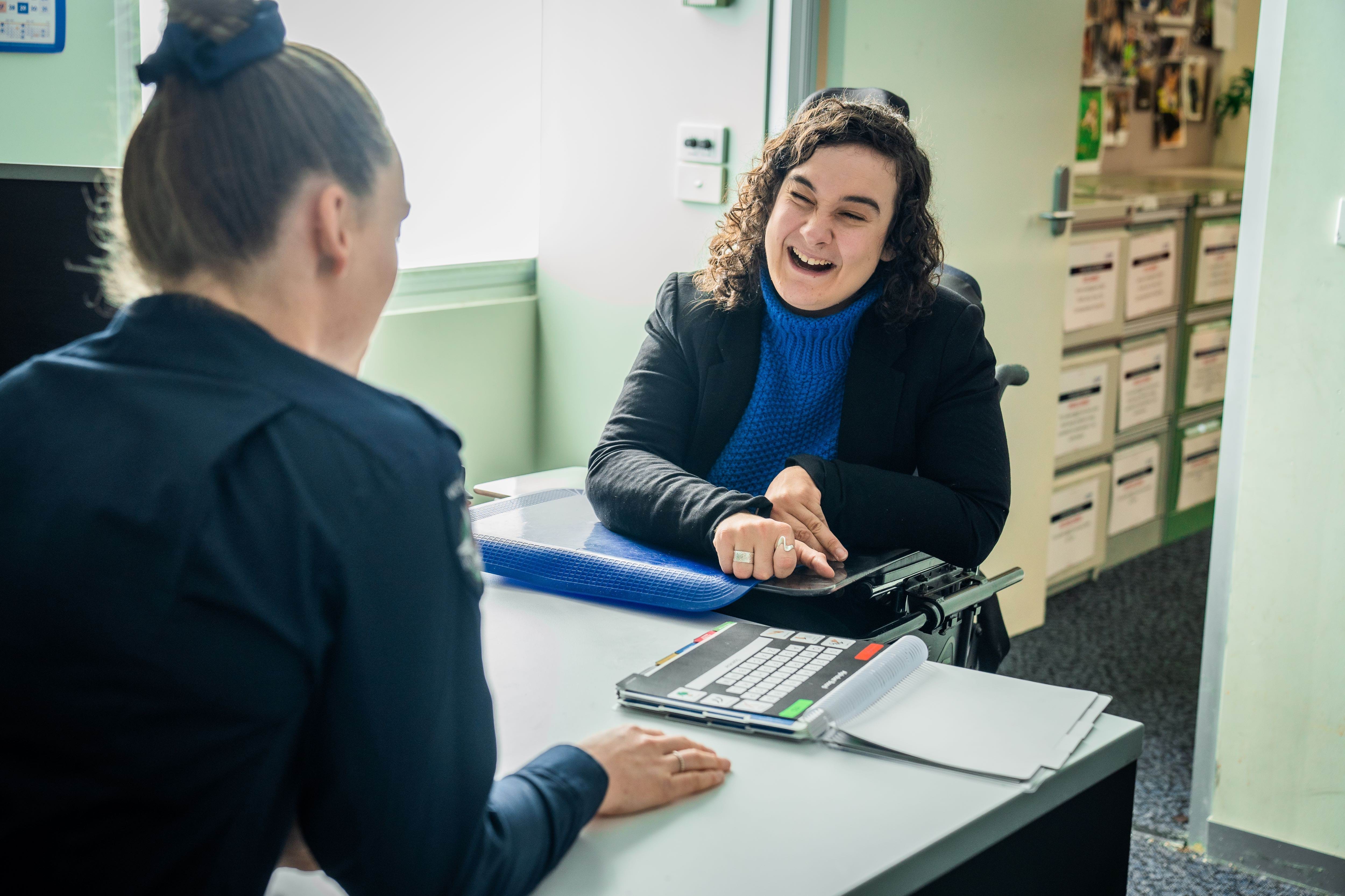 Disability Liaison Officer sitting in an office space, speaking with a member of the public.