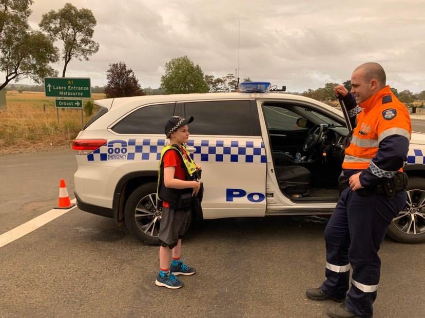 Victorian bushfires 2019-2020 - A boy in a police vest talking to an officer by a police car