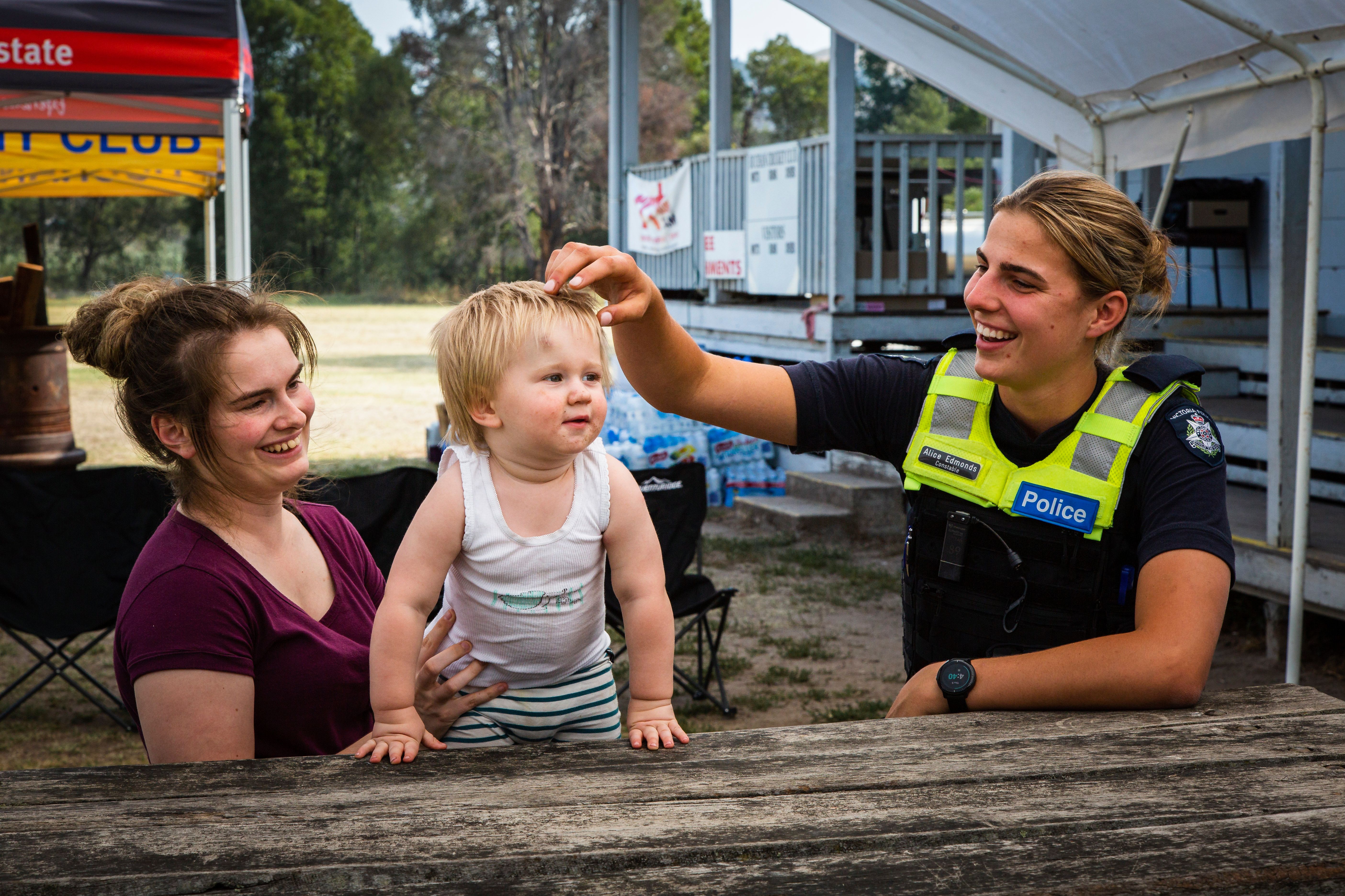 Victorian bushfires 2019-2020 - Female police officer chatting and smiling with a mum and toddler