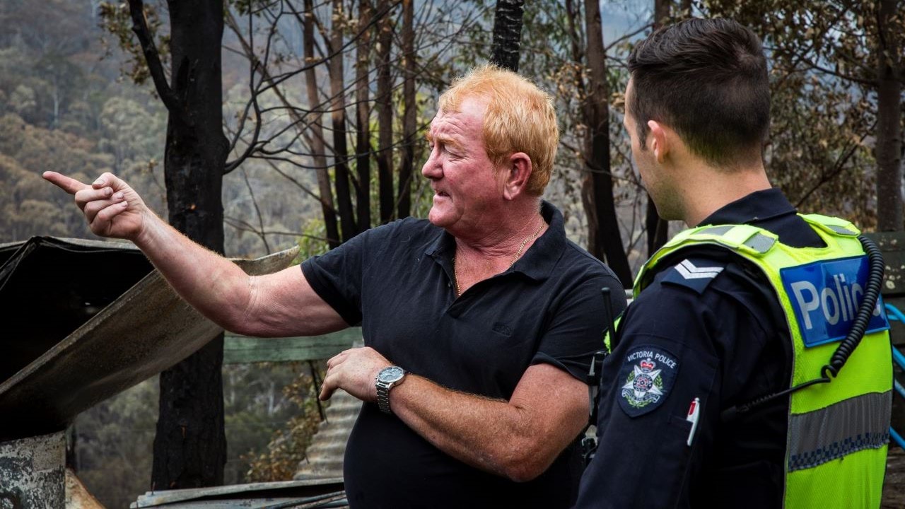 Police officer in uniform, talking to a member of the community in a fire affected area