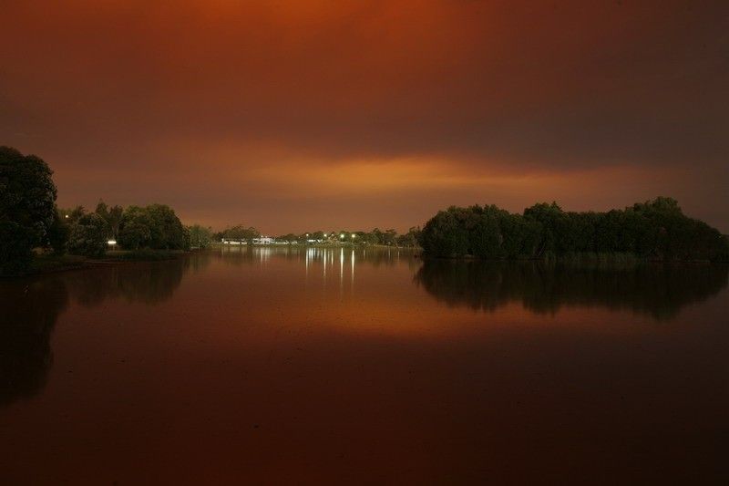 Victorian bushfires 2019-2020 - Distant marina lights with black and orange sky reflecting on water surface