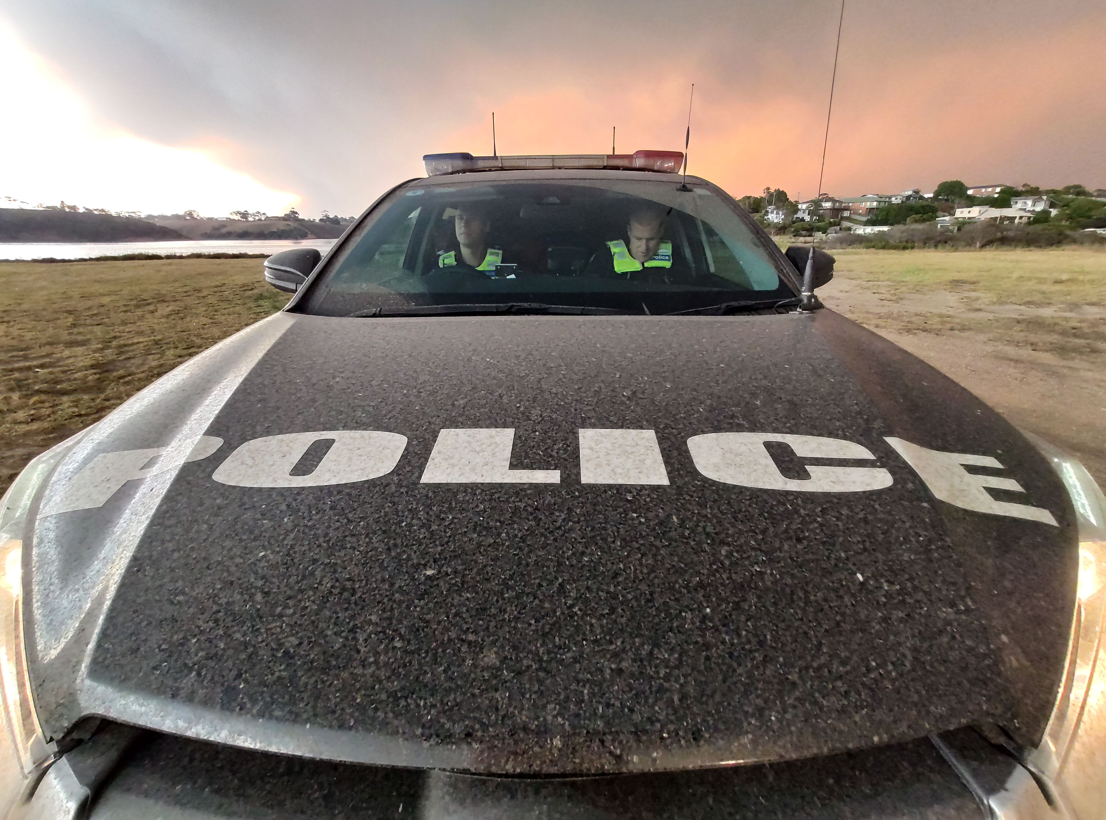 Victorian bushfires 2019-2020 - Two officers in a police car with smoky sky behind