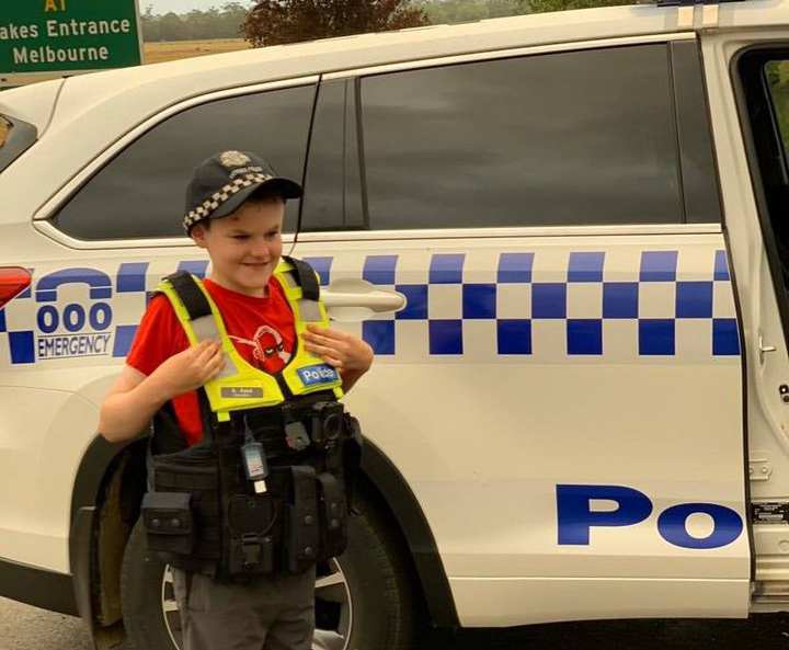 Victorian bushfires 2019-2020 - A smiling boy in police vest next to police car