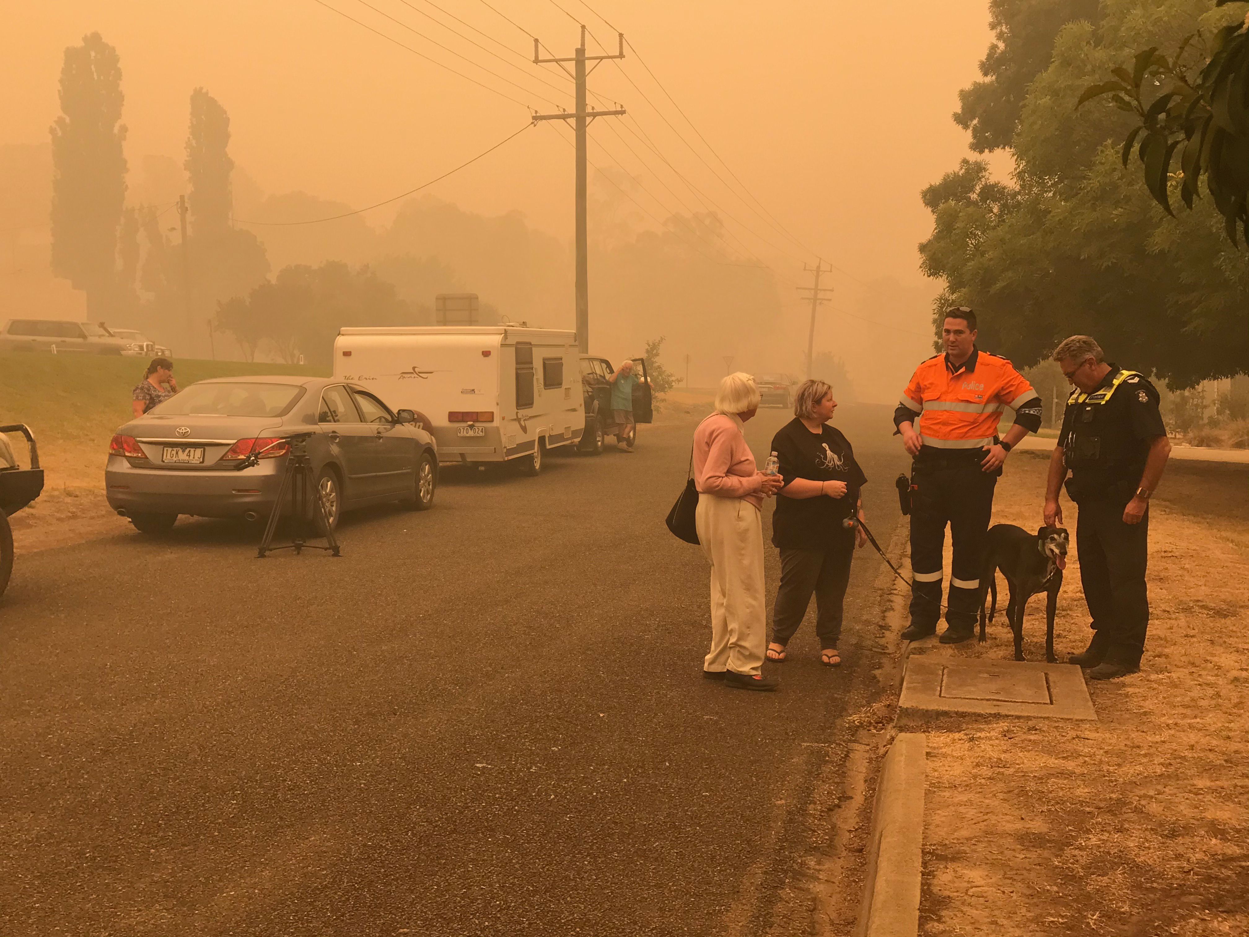 Victorian bushfires 2019-2020 - Two officers talking to community members outside in smoky conditions