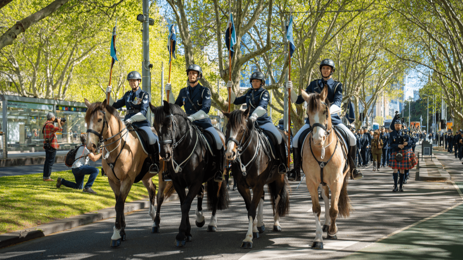 Four officers riding horses lead the procession towards the Police Memorial.
