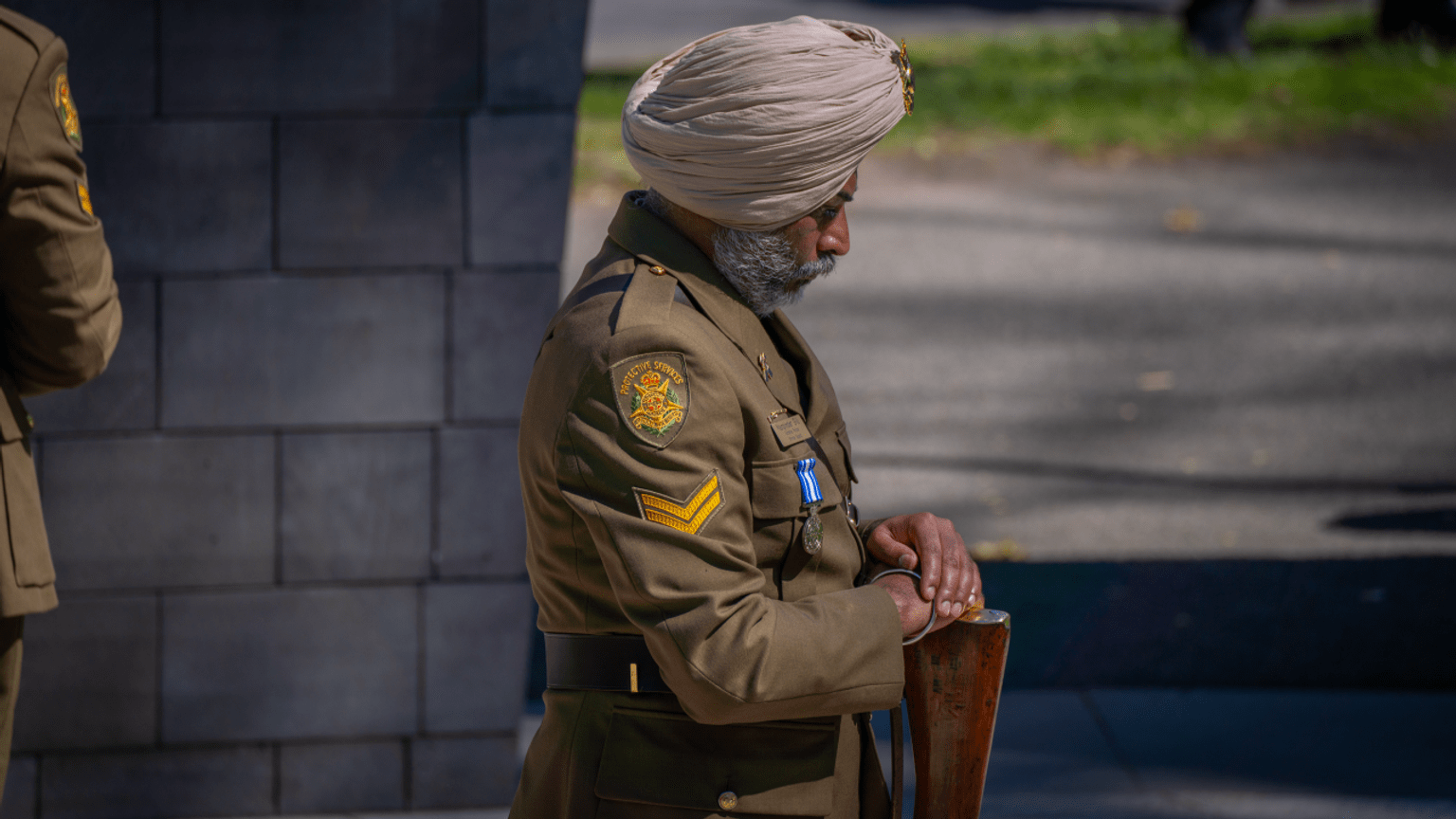 A Protective Services Shrine Guard bows his head as he stands at the Police Memorial.