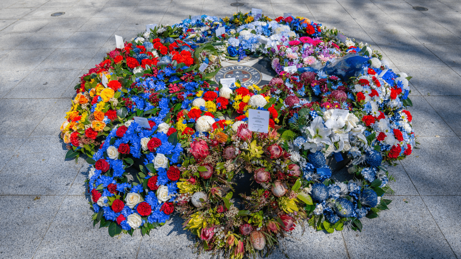 Wreaths of flowers in many colours, laid in a circle at the Police Memorial.
